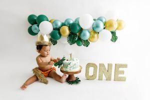 French Valley California 1st birthday photographer: Baby boy in safari outfit smashes first birthday cake.