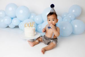 Menifee cake smash photographer pic of baby boy in 1st birthday party with cake and blue balloons.