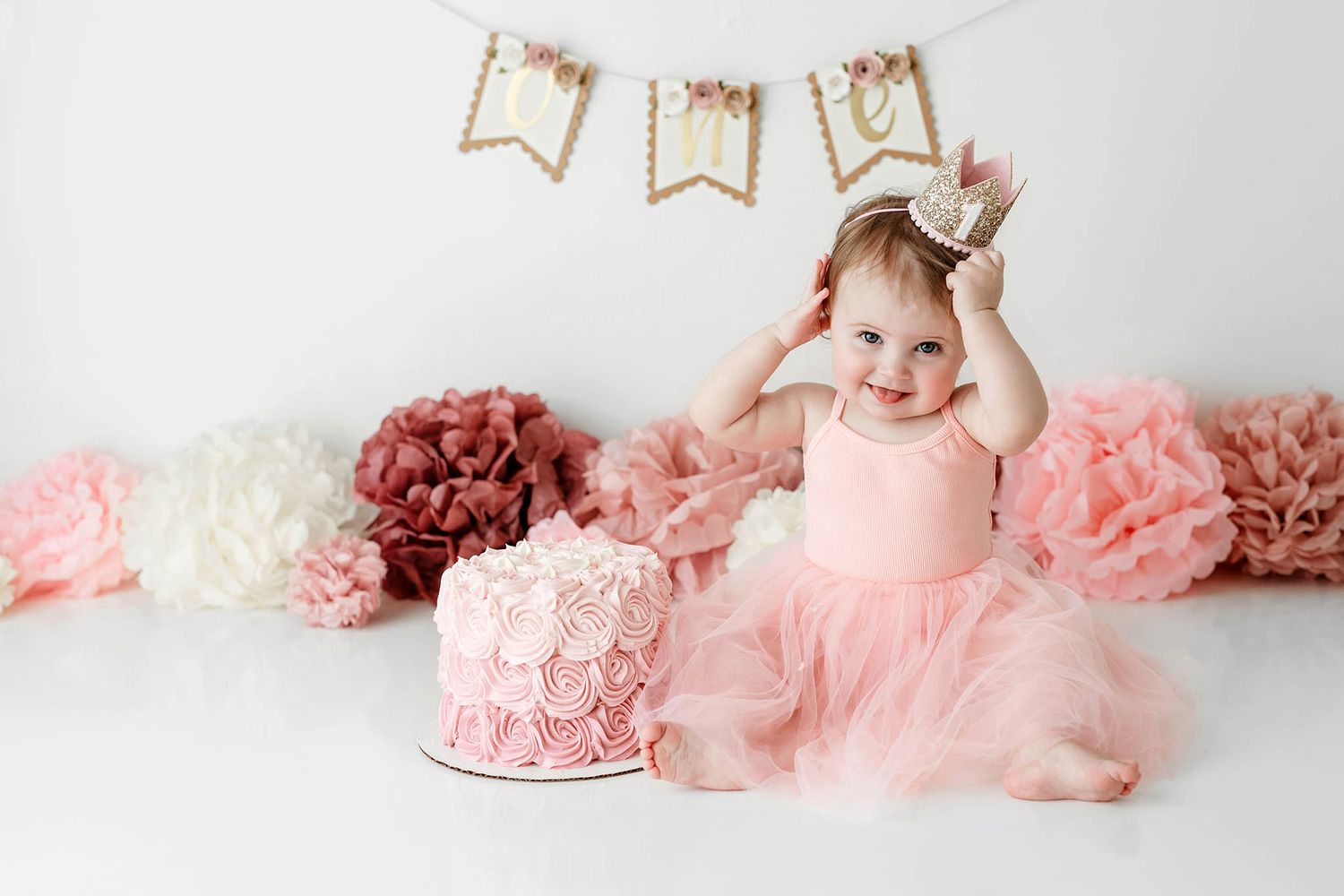 Baby girl in pink tutu dress with gold crown celebrates first birthday with photoshoot by Menifee cake smash photographer.