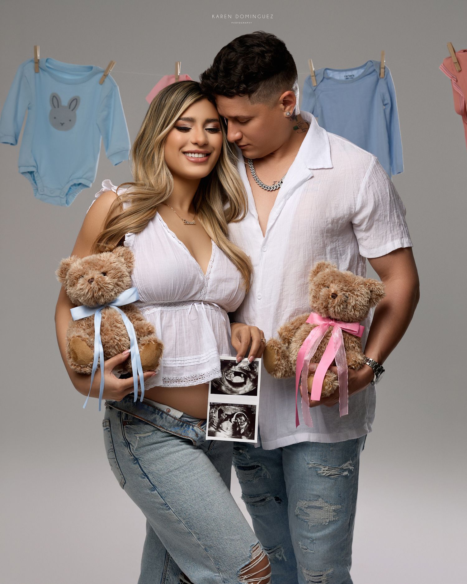 Couple holding teddy bears with blue and pink bows and ultrasound photos at a gender reveal maternity photoshoot.