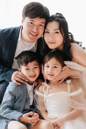 A happy family wearing white and gray outfits poses together for intimate portrait photos.一家人穿著白色和灰色服裝，幸福地合影。