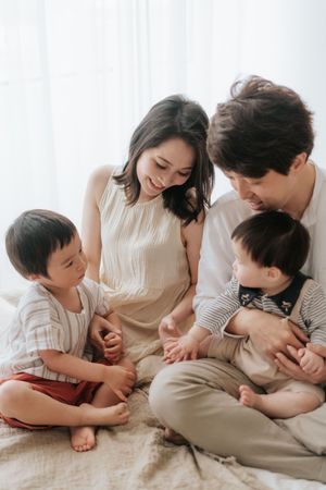 A heartwarming series of candid family moments showing playful interaction and bonding on a light-colored bed.一系列溫馨的家庭瞬間，展現了一家人在淺色床上嬉戲互動、增進感