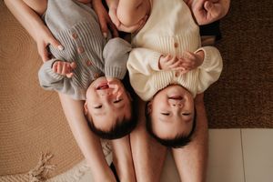 Two people lying on floor laughing together during casual indoor photoshoot.兩人躺在地板上，在室內隨意拍照時一起大笑。