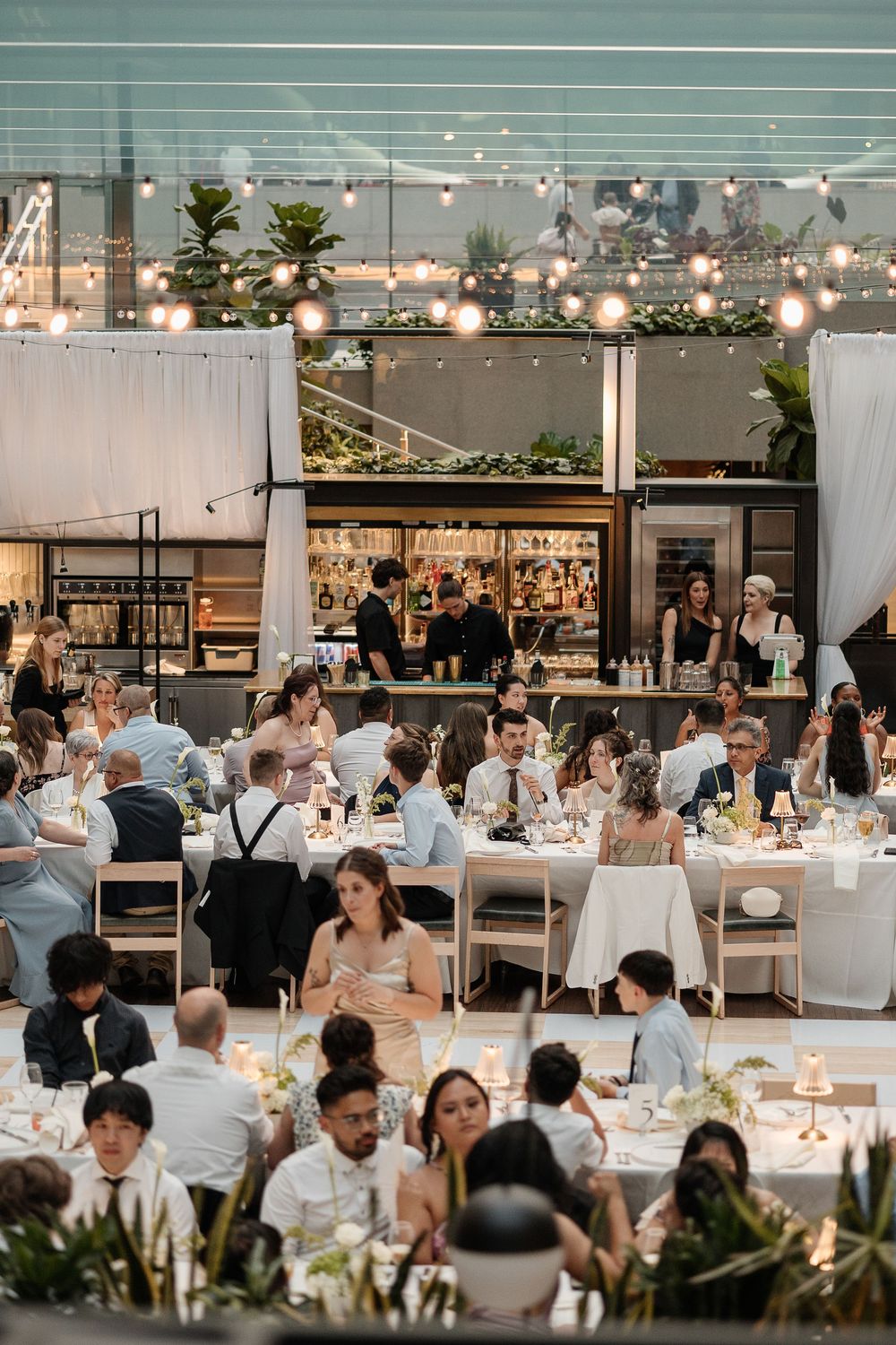 Elegant wedding reception with guests seated under string lights, captured by Aliza Dworkind at Le Cathcart, a modern Montreal wedding venue