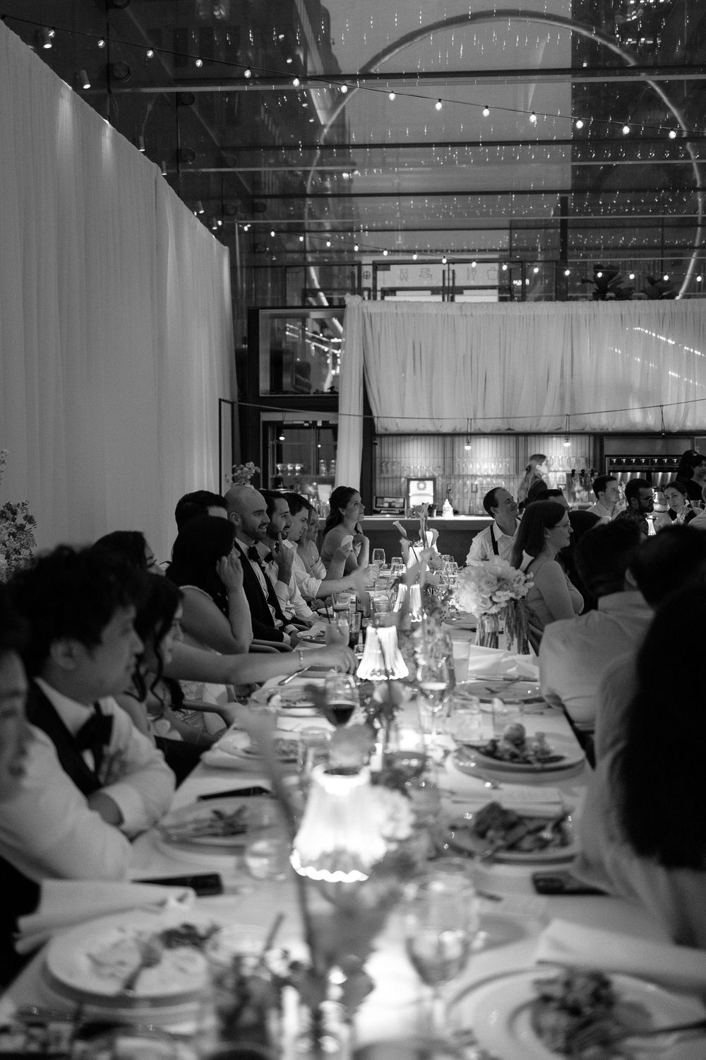 Guests seated at elegantly set tables during a formal wedding reception dinner in a decorated banquet hall.