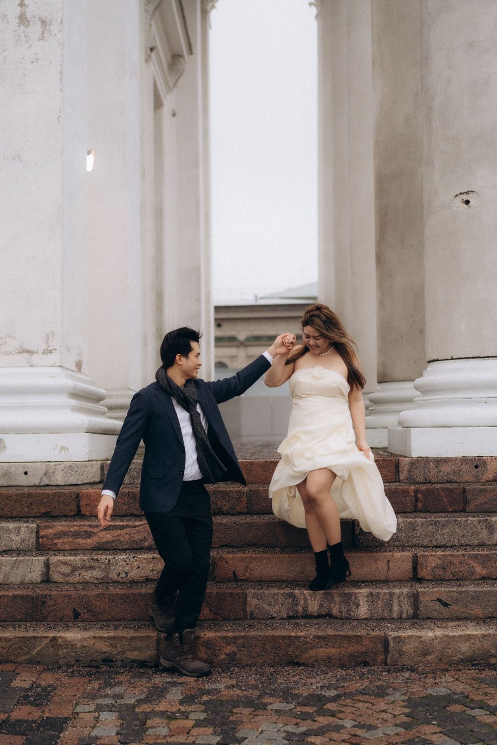 Engaged couple walking down the steps of Helsinki Cathedral during an editorial engagement session