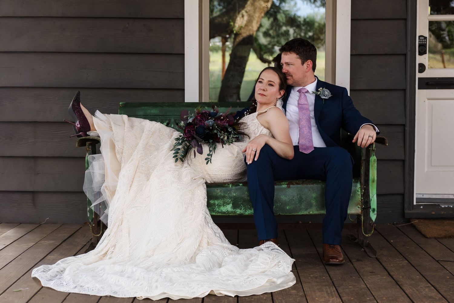 A candid and natural wedding portrait of a bride and groom lounging on a vintage bench outside a local Buda, Texas venue.