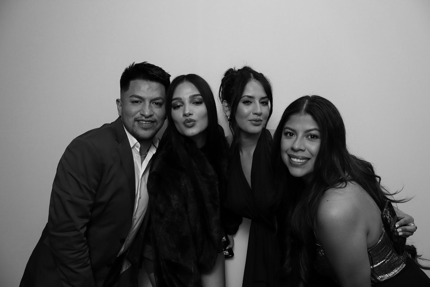 Black and white photo of four people smiling and posing together at a formal event.