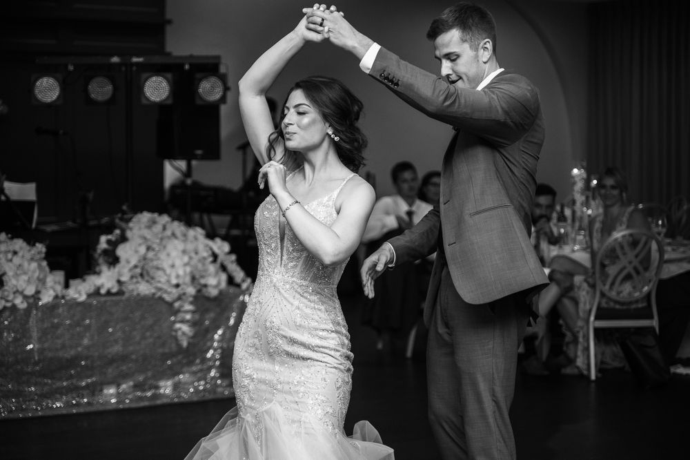 Bride and groom share first dance at wedding reception, black and white photo.