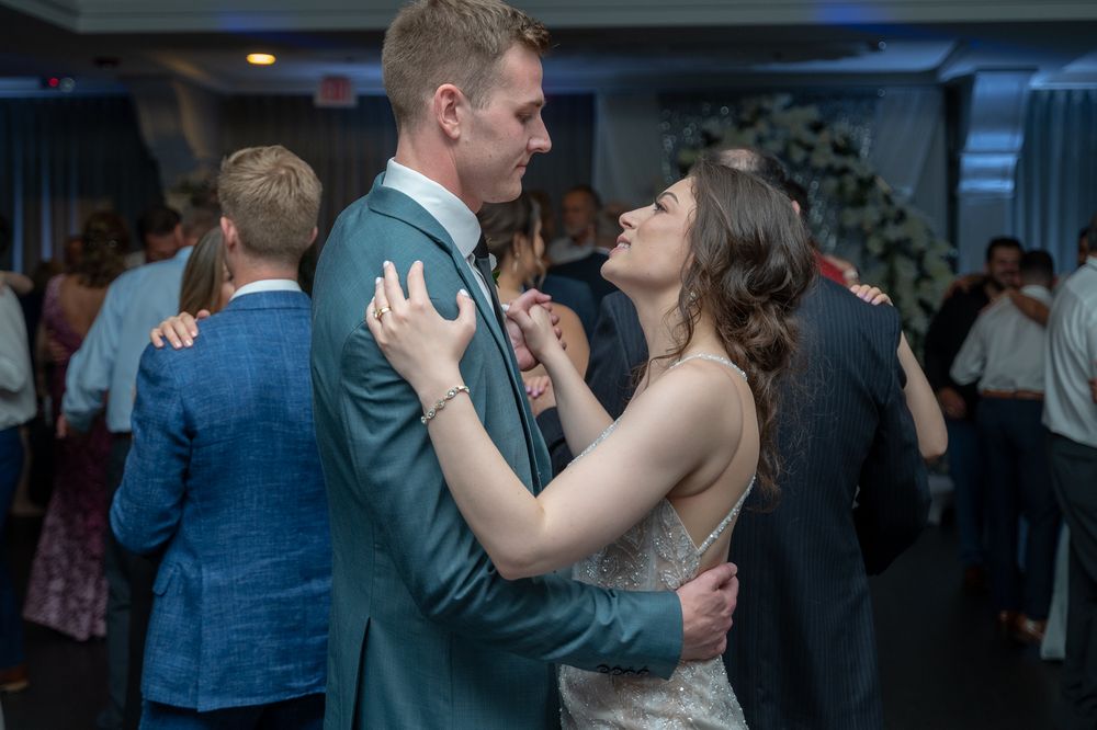 Couple sharing a romantic slow dance at a wedding reception in a softly lit ballroom.