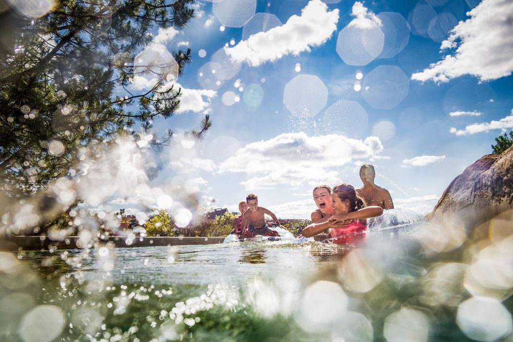 Kayakers paddle on sparkling water under blue skies with water droplets creating a dreamy lens effect.