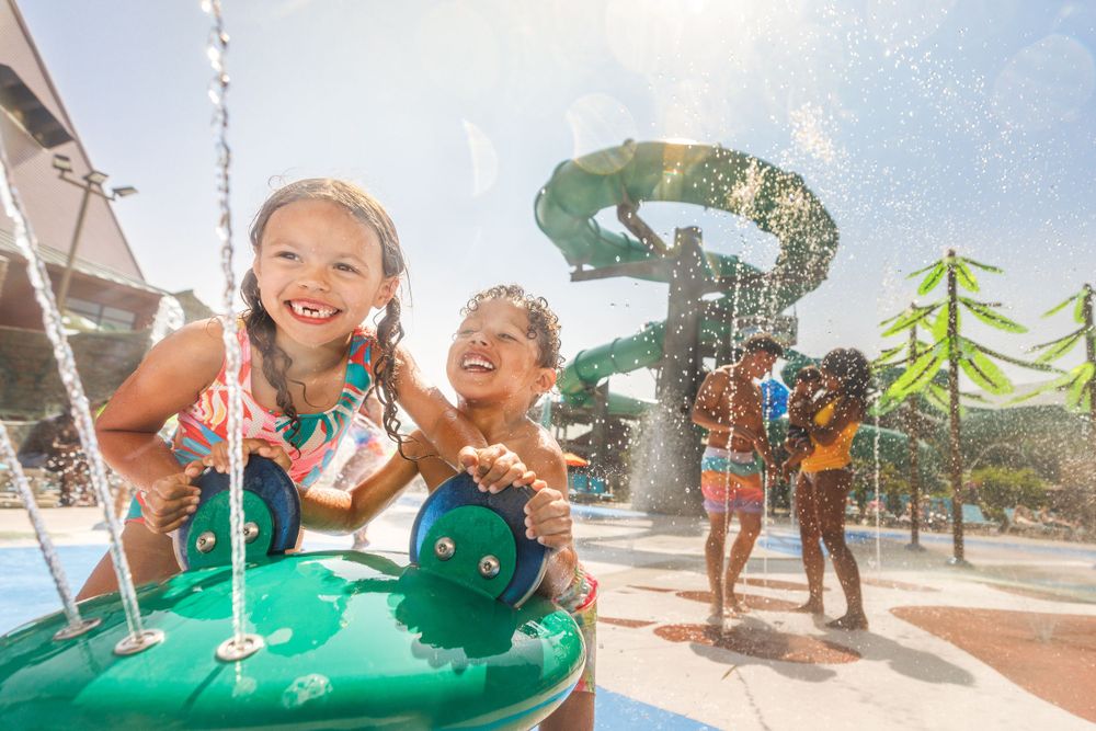 Kids having fun playing in the water at an outdoor water park with colorful slides and splash features on a sunny day.