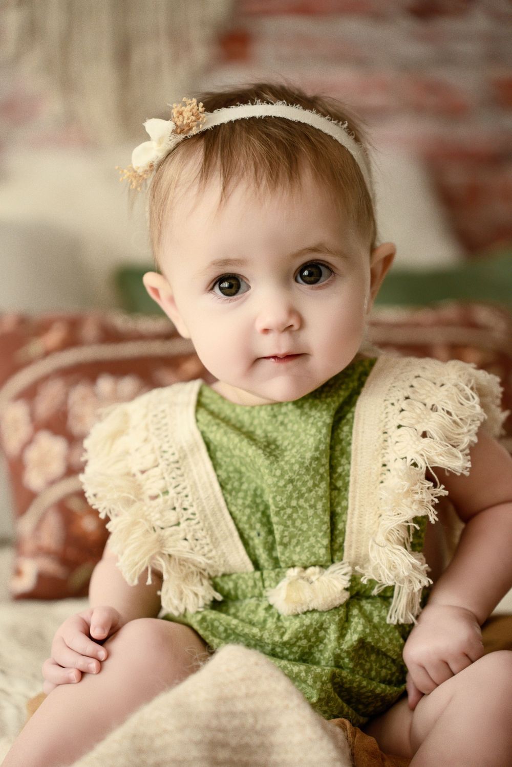 Professional portrait of baby in vintage-style green and cream lace outfit.
