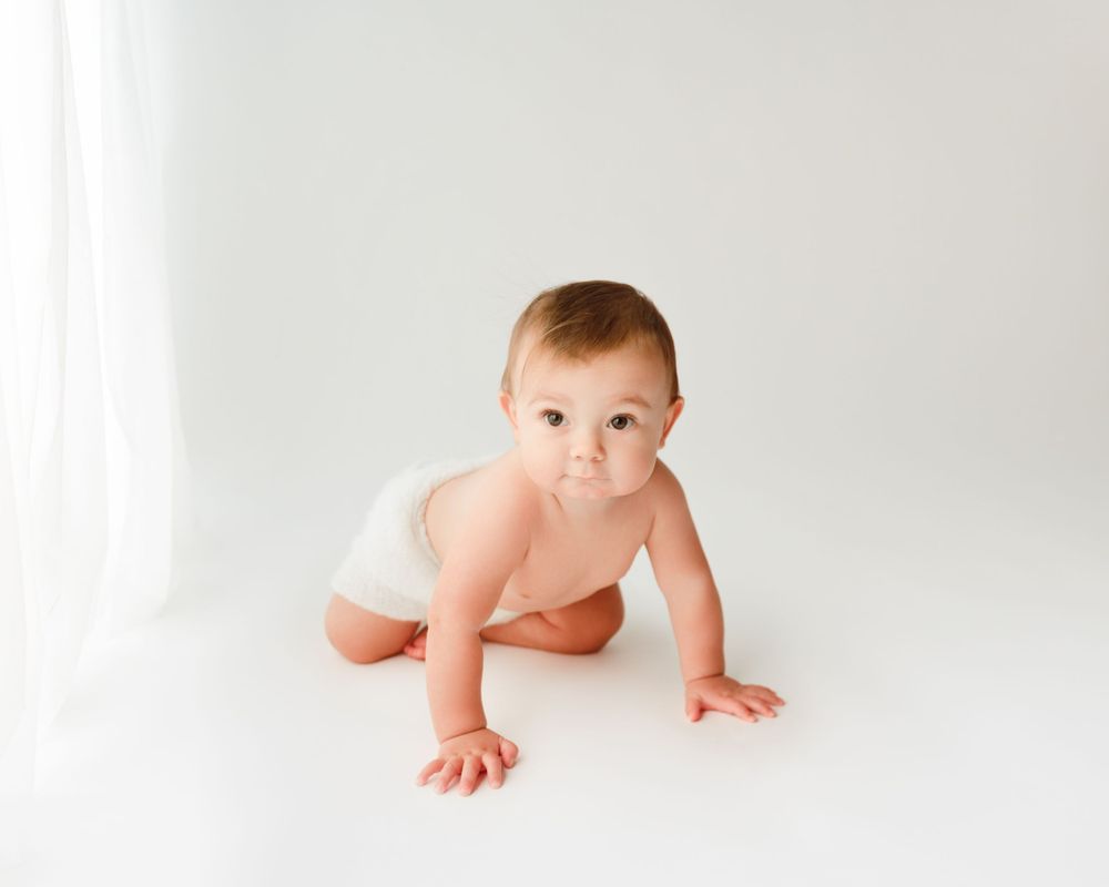 Minimalist studio crawling portrait on white background.