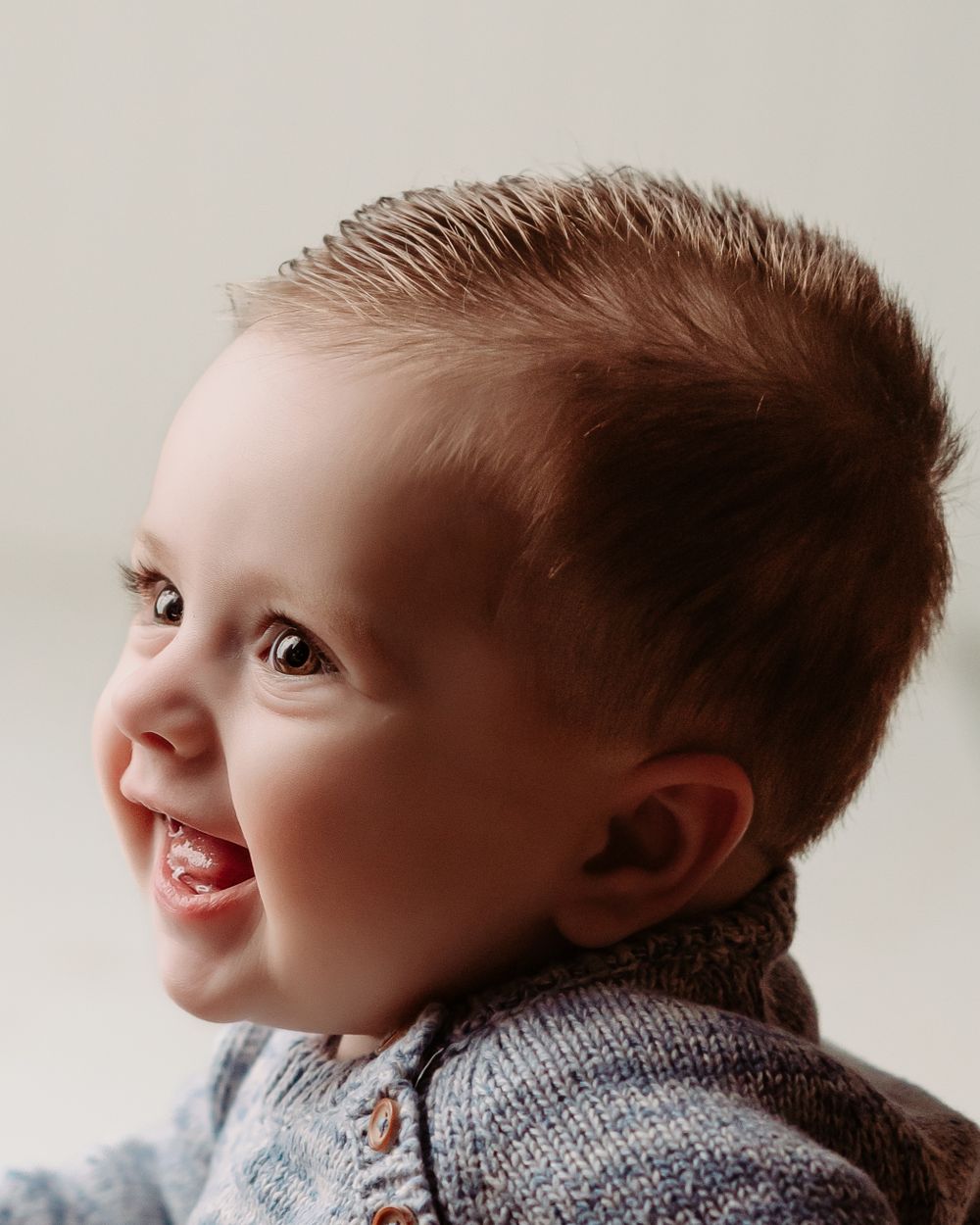Close up studio portrait wearing gray knit sweater against light background.