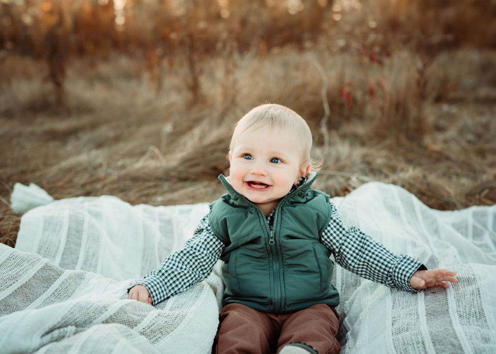 Winter portrait on white blanket wearing green puffer vest outdoors.