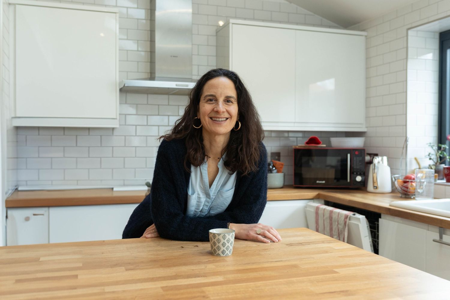 confidence coach smiling with a coffee in her kitchen for a personal branding shoot in Brighton