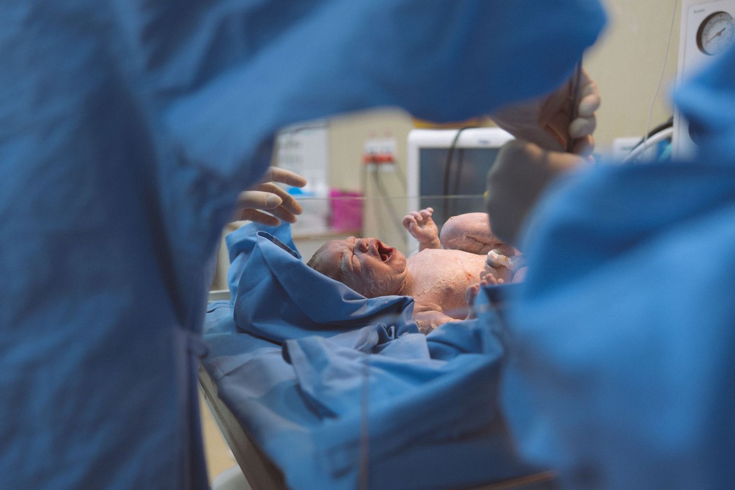 Medical professionals in blue scrubs work together during a surgical procedure in an operating room.