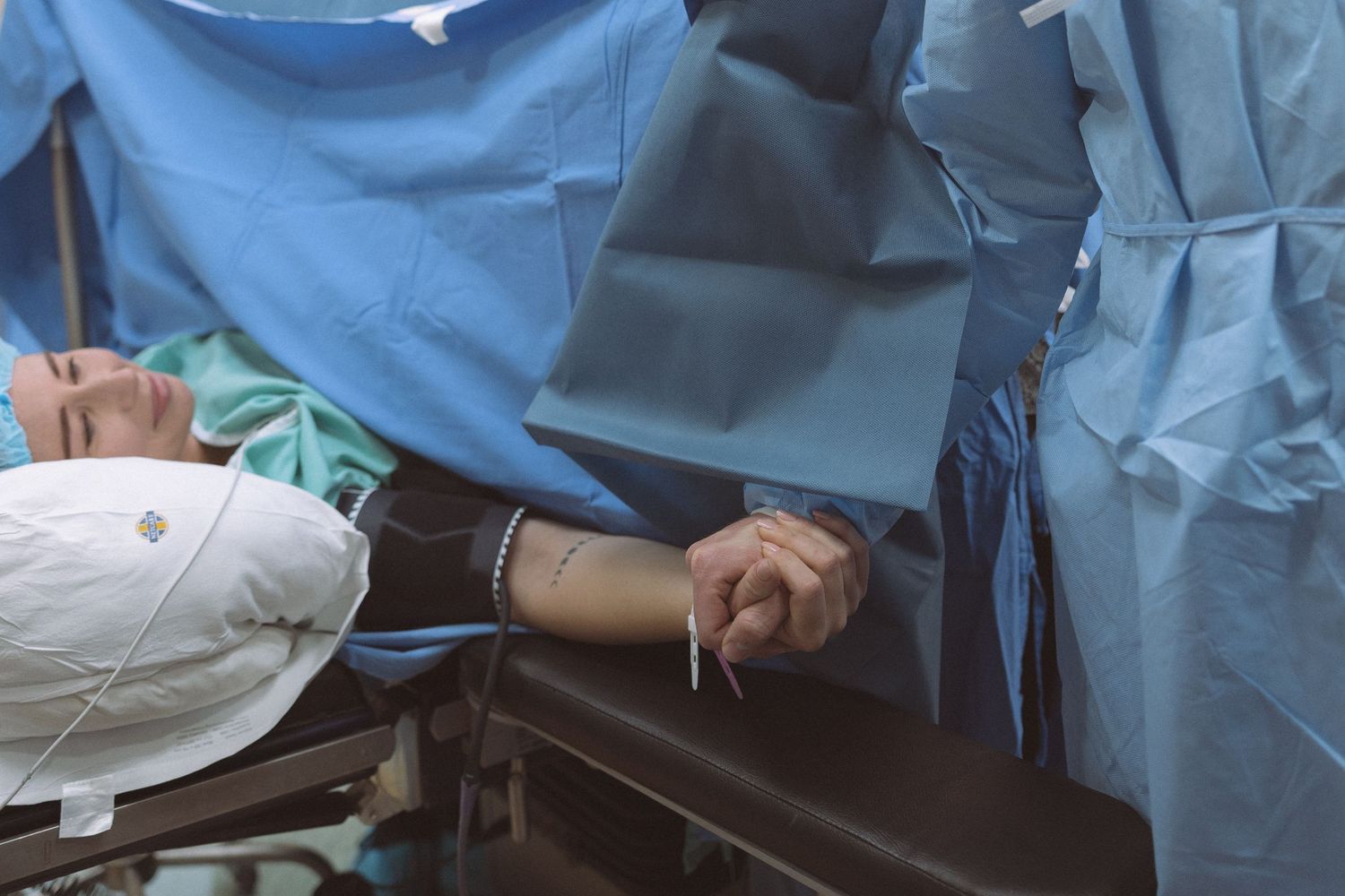 Medical professionals in blue scrubs and surgical masks perform a surgical procedure in an operating room.
