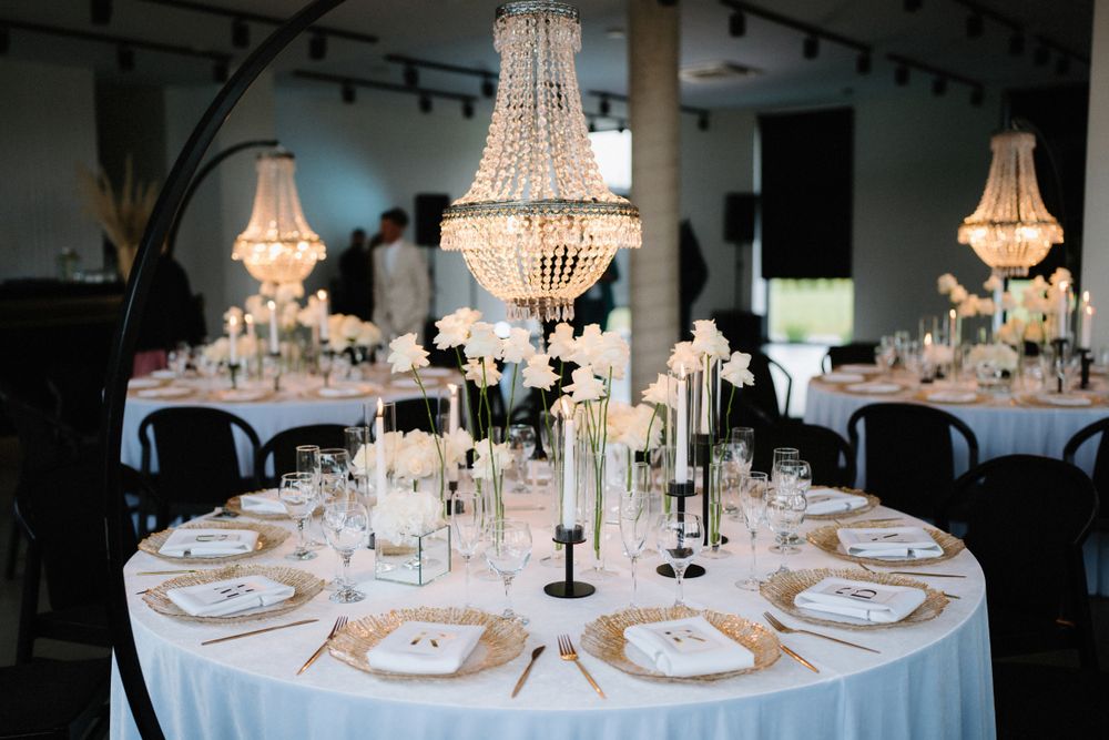 Round reception tables decorated with crystal chandeliers and white linens for an elegant wedding.