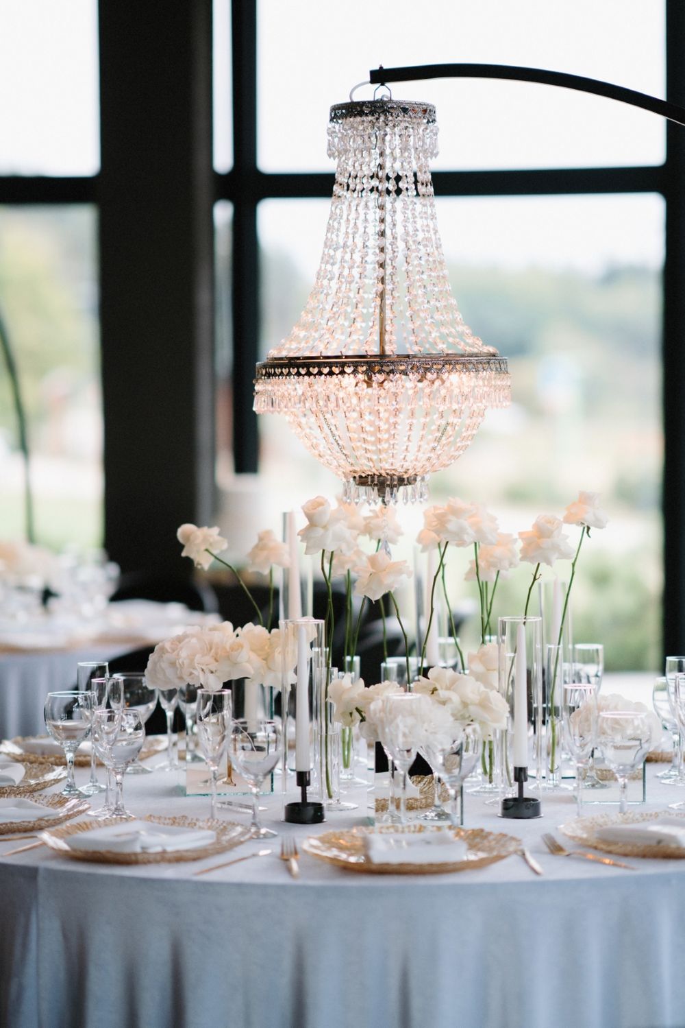 Luxurious wedding table settings with crystal chandeliers and white floral arrangements.