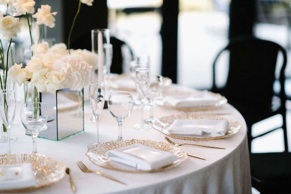 Detailed view of elegant place settings with crystal glassware and white floral accents.