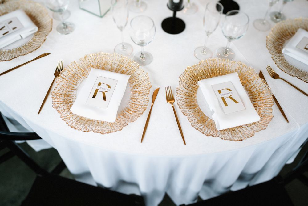 Close-up of wedding reception table details with gold accents and white linens.