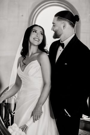 Black and white portrait of newlyweds sharing a romantic moment under an arched doorway.