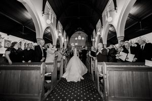 Wedding ceremony in progress inside traditional church with wooden pews and arched ceiling.