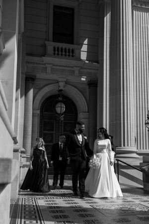 Elegant wedding couple standing at entrance of historic building with classical architecture.