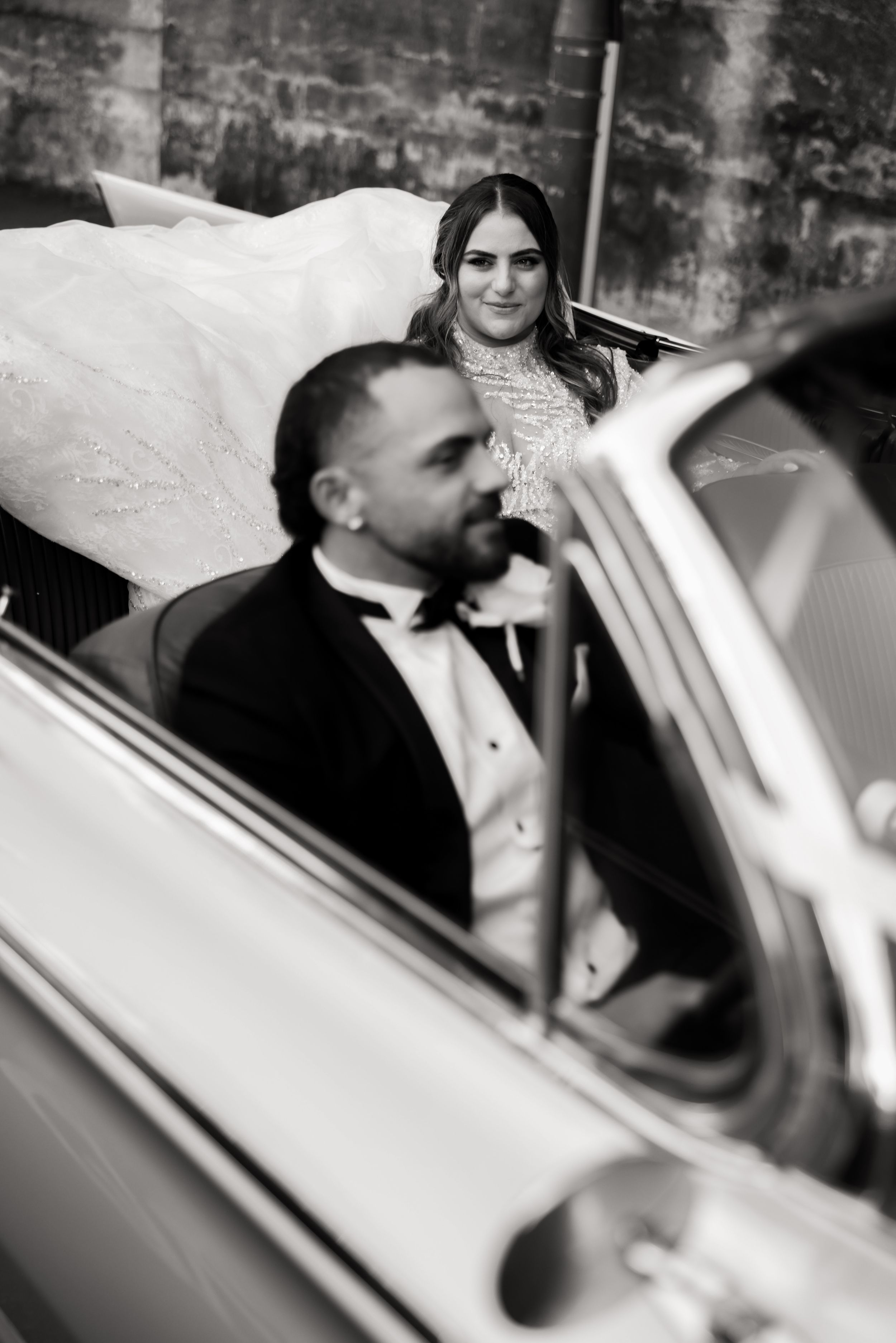 Black and white photo of elegant vintage car with formal attire.