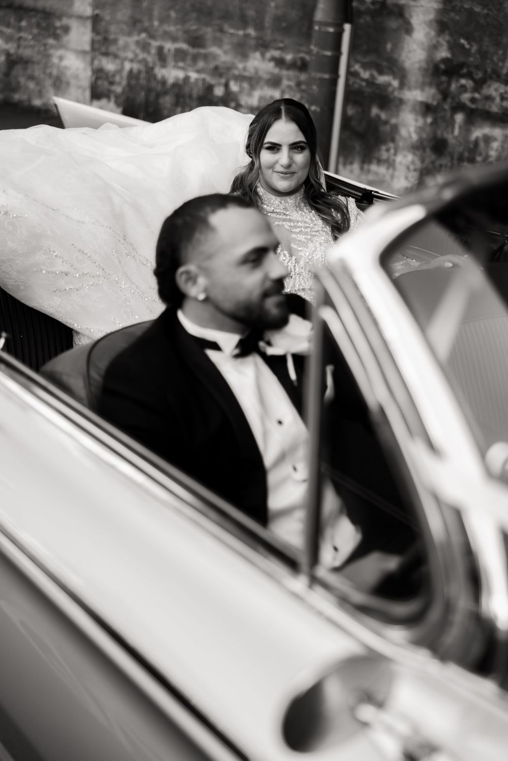 Black and white photo of elegant vintage car with formal attire.
