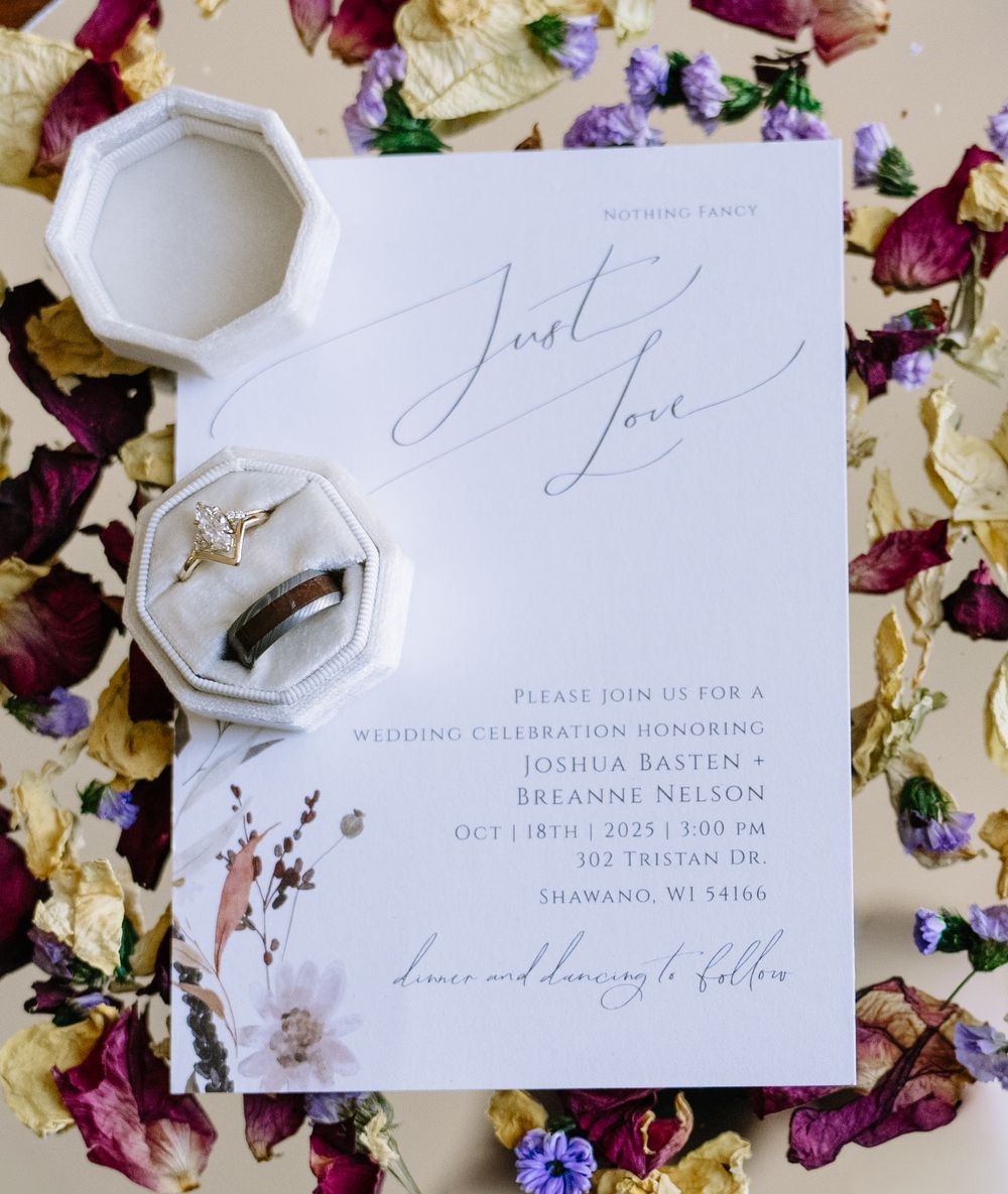 Elegant wedding invitation suite with calligraphy displayed with dried flower petals.