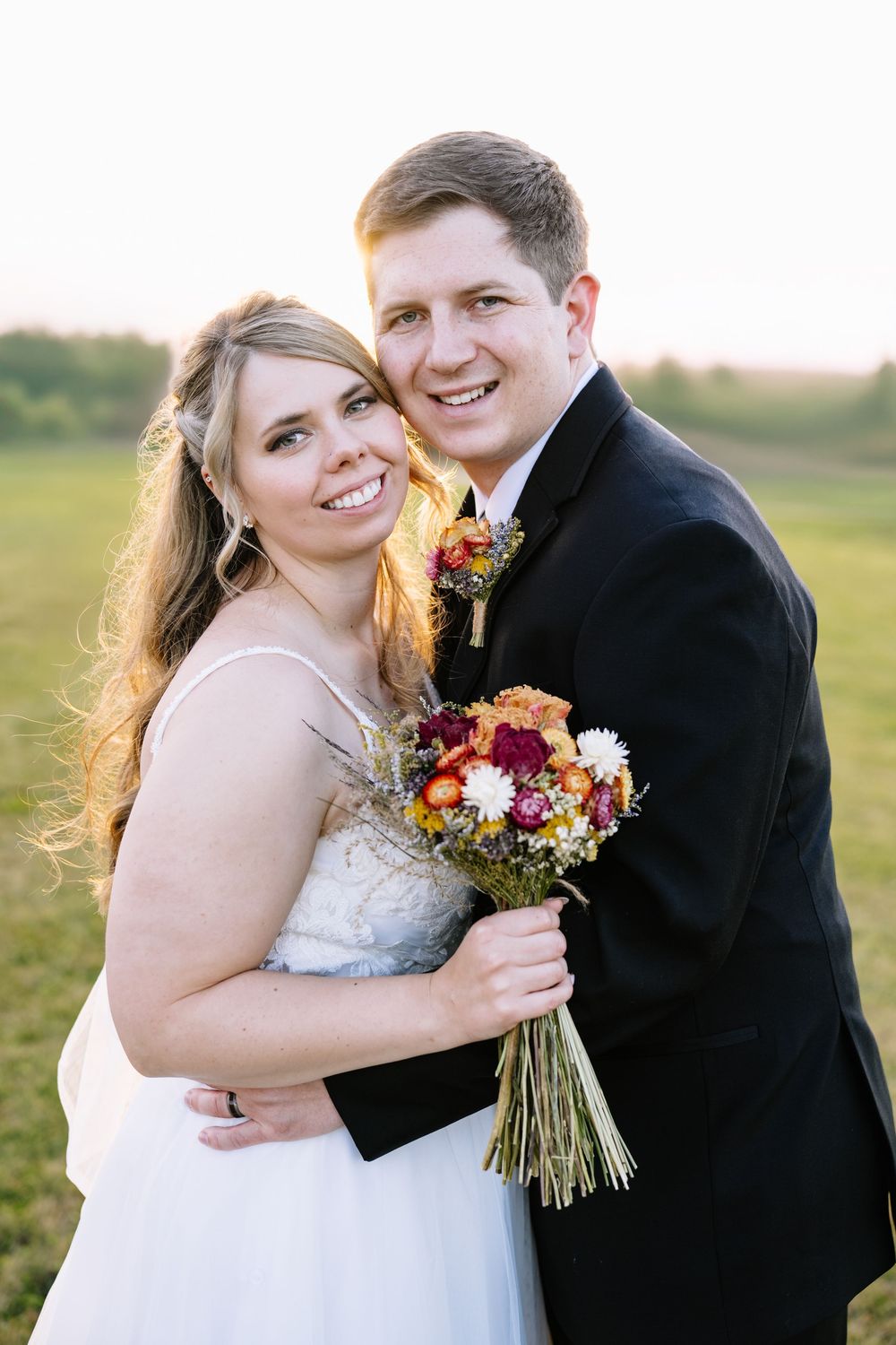 Romantic couple portraits in golden sunlight with colorful autumn bouquet.