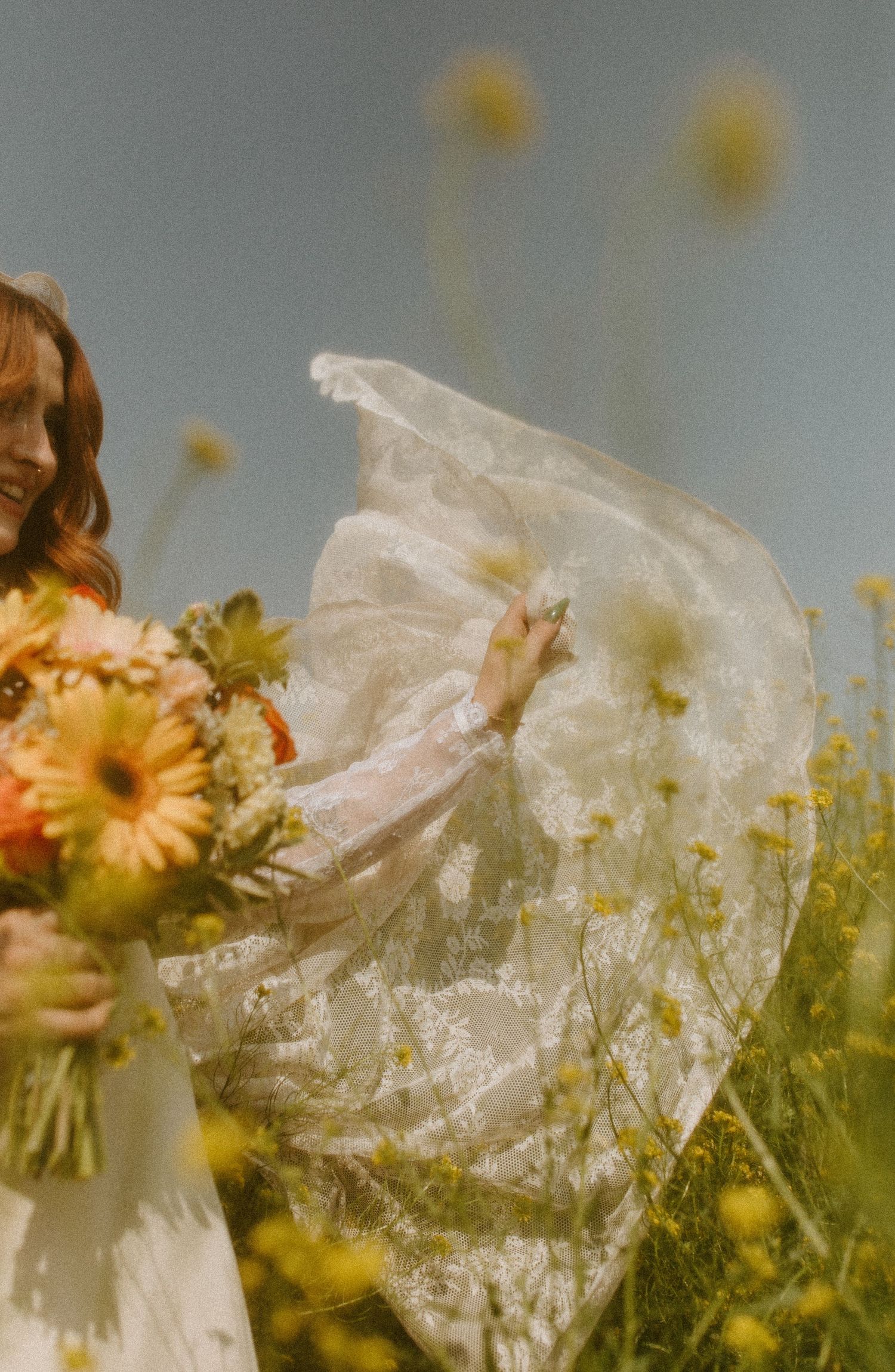 Romantic portrait of person in white dress holding flowers in sunny meadow.