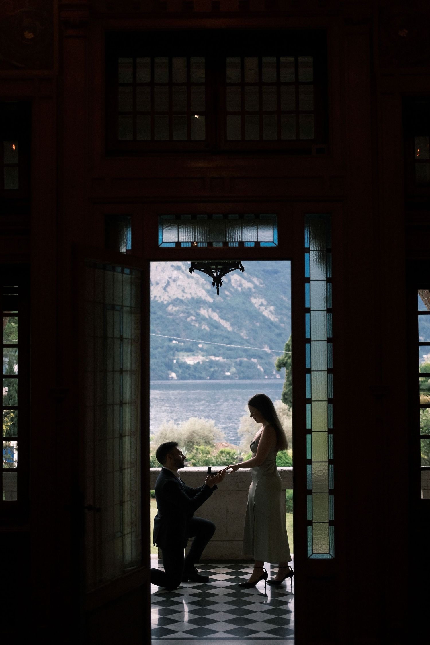 Man proposing to a woman in a doorway overlooking a lake