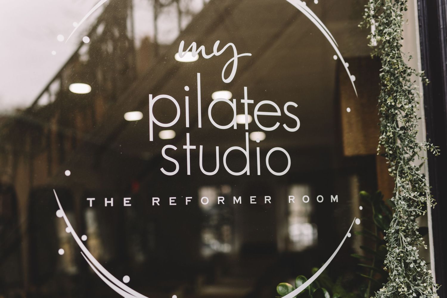 Storefront window sign displaying 'Pilates Studio - The Reformer Room' in elegant white lettering.