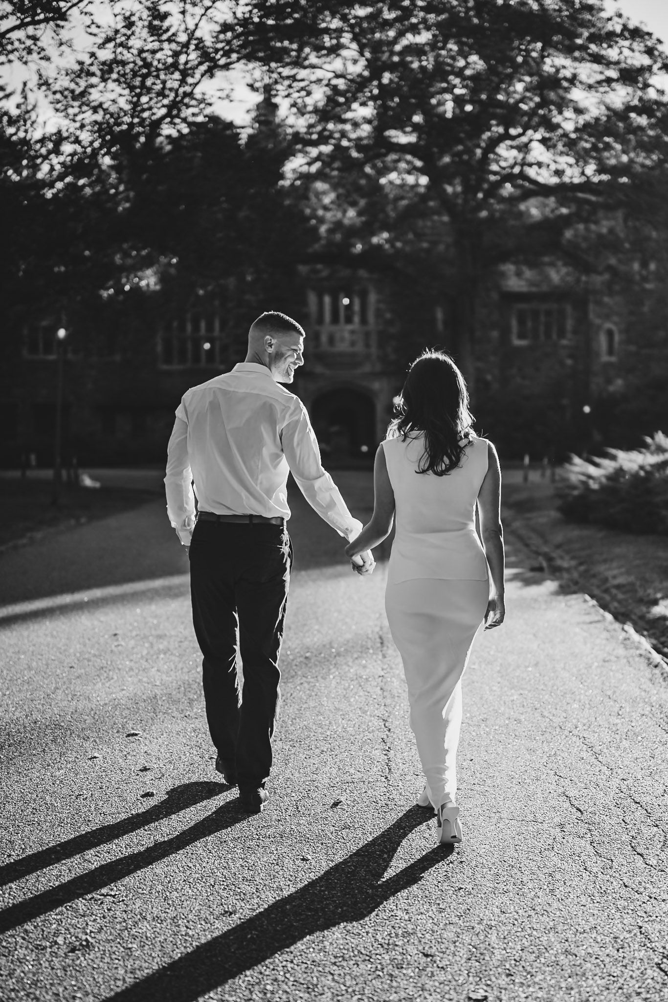 Black and white photo of a couple walking on a path casting long shadows.