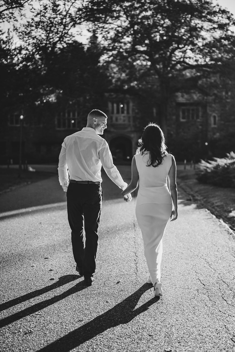 Black and white photo of a couple walking on a path casting long shadows.