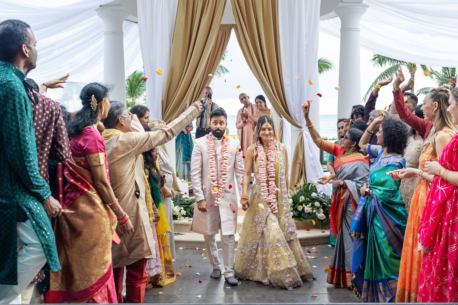 Wedding guests in colorful traditional attire dance and celebrate during a festive reception ceremony.