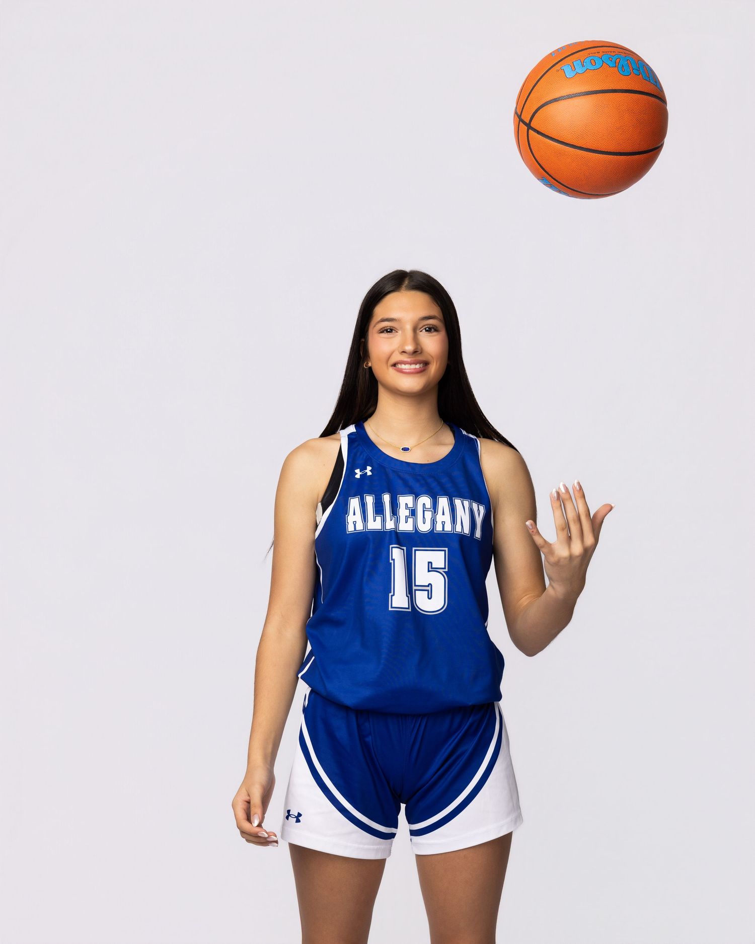 Basketball player in blue Allegany uniform poses with ball during team photo session.