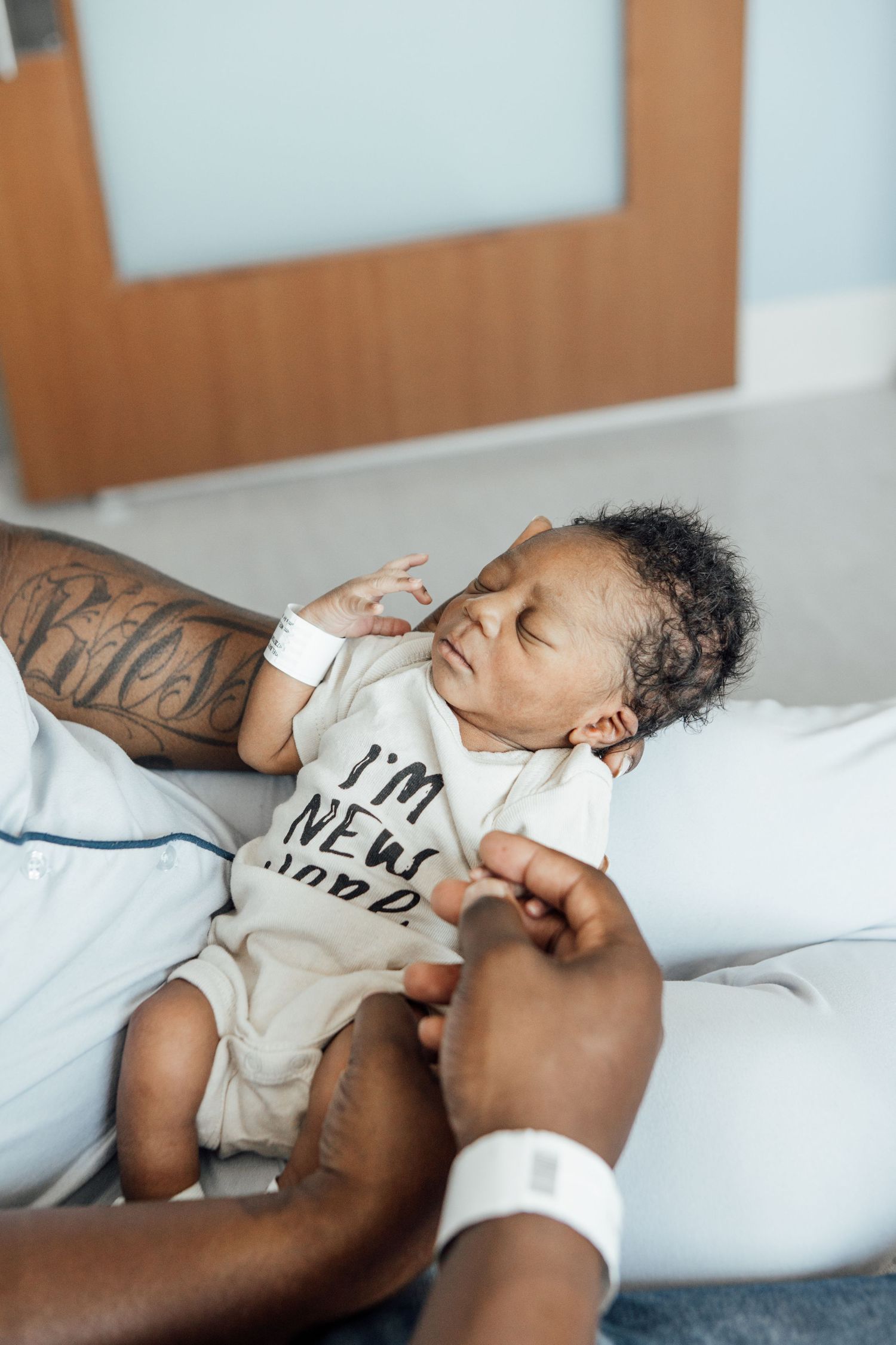 Parent and baby lying together on white bedding in intimate moment.