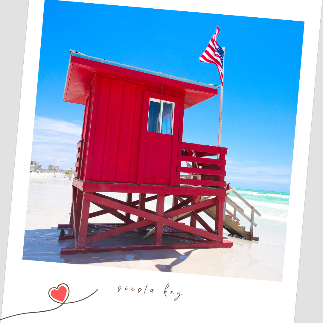 A bright red lifeguard tower stands on a white sandy beach against a vibrant blue sky and ocean backdrop. Siesta Key Florida Flying Dress
