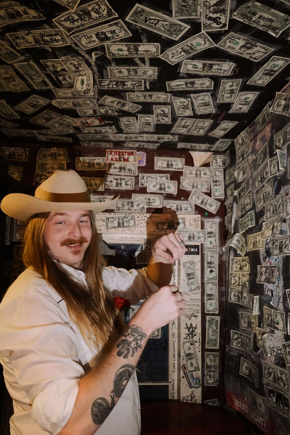 A view of a bar ceiling completely covered in signed dollar bills.