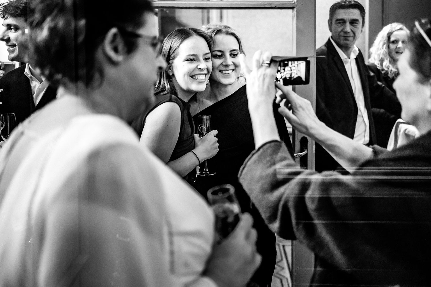 Black and white photo showing wedding guests mingling and socializing at an elegant reception.