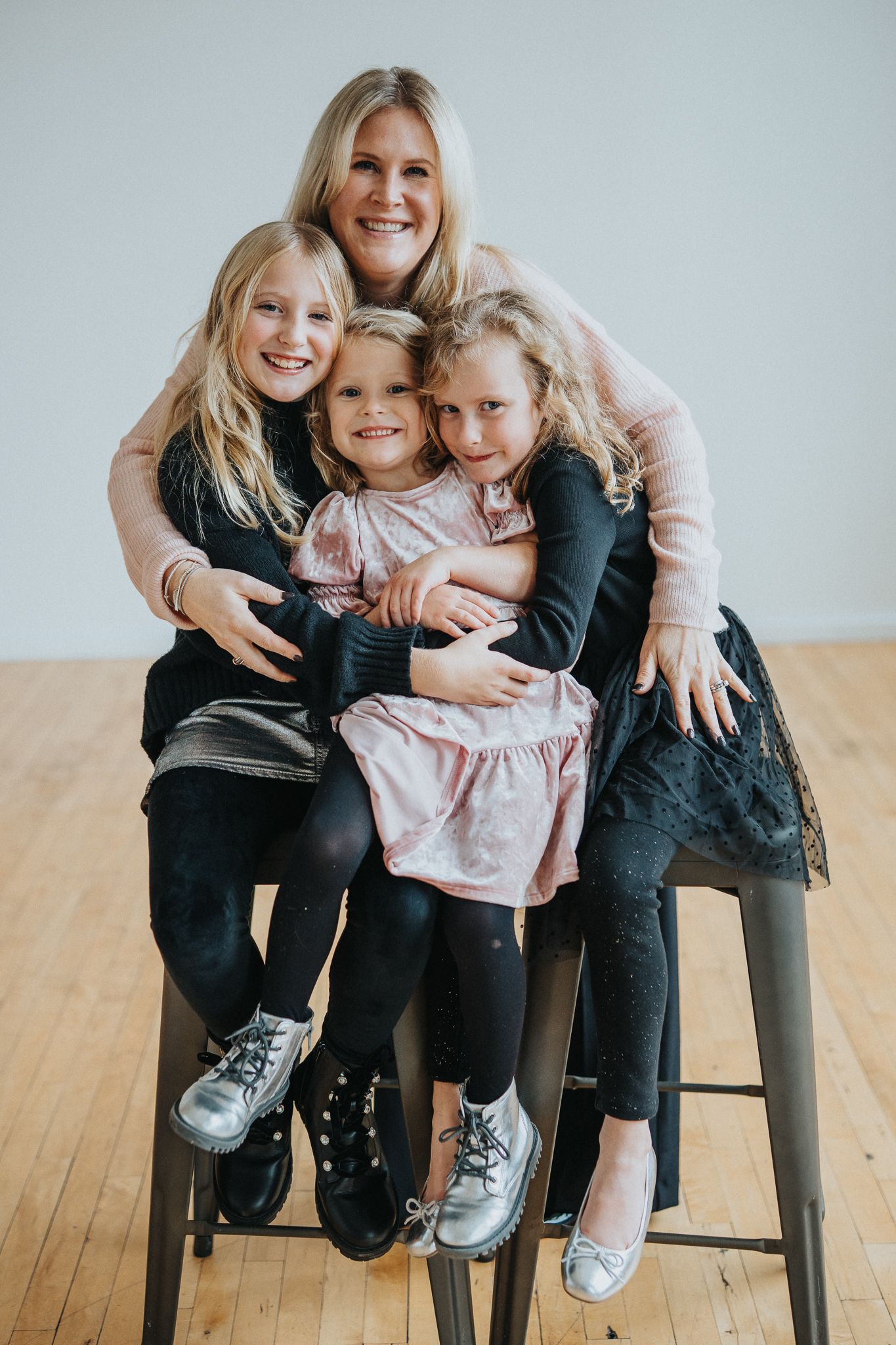 A family shares joyful moments together while sitting on wooden chairs in a bright indoor setting.