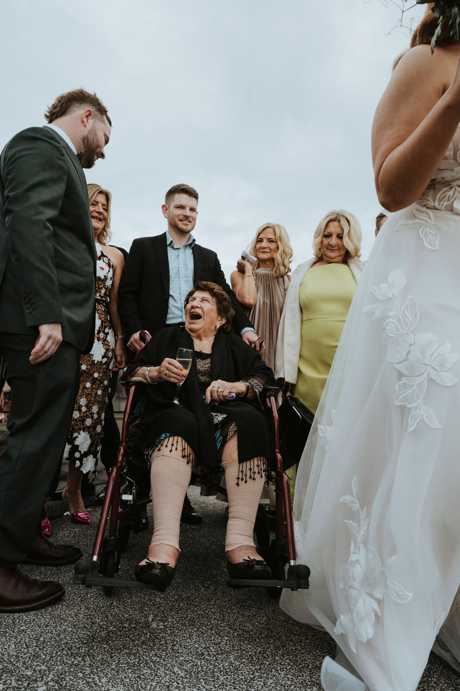Happy wedding guests share a candid moment and hearty laughter during an outdoor reception celebration.