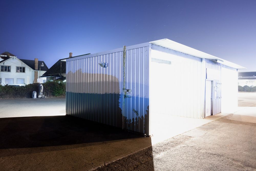 Row of industrial storage units against a bright blue sky with metal siding.