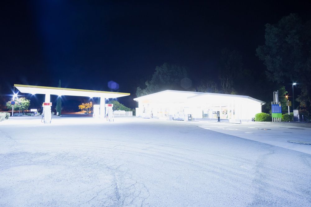 Snow covered parking area with bright lights illuminating the space at night.