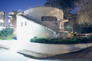 Modern architectural structure with curved walls photographed at night.